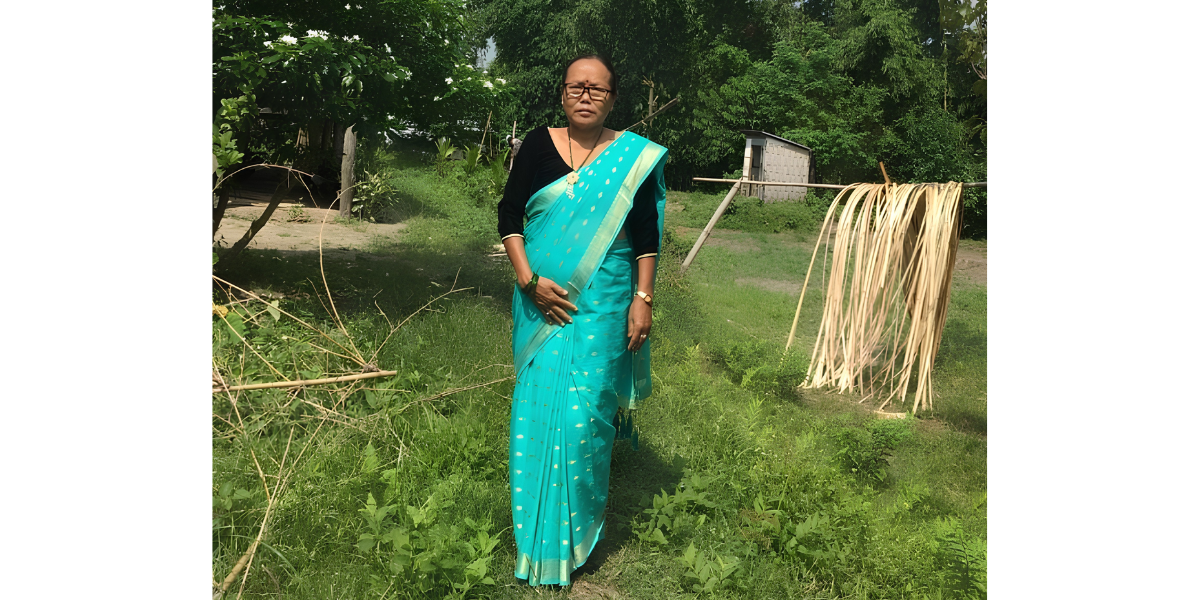 Lola, a grandmother at a center in Nepal, stands in a yard wearing a teal sari