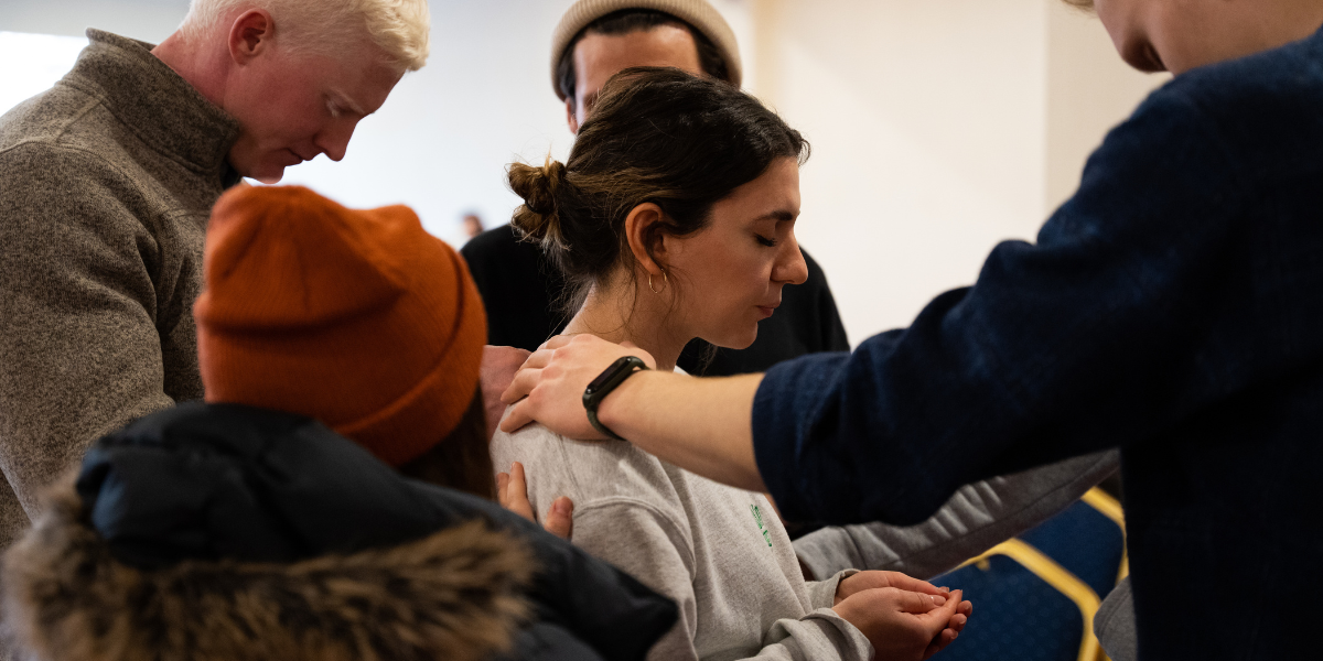 People gathering around a young woman to pray for her