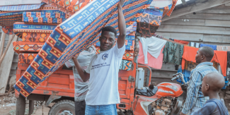 A man holding a mattress on his head, part of a supply distribution in the DRC